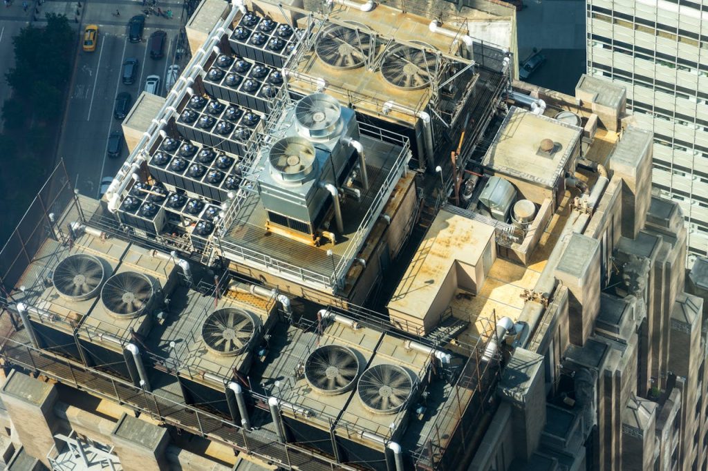 aerial-photography-of-brown-concrete-building-2539462 High-angle shot of HVAC units on a city buildings rooftop, showcasing industrial infrastructure.